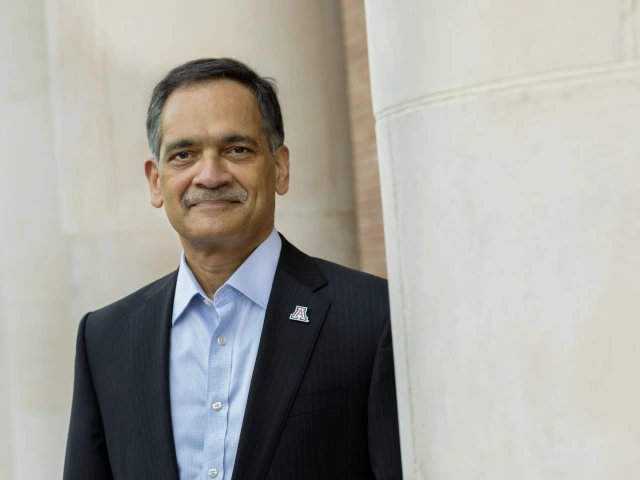 President Garimella looking at camera with his shoulder behind a large white column